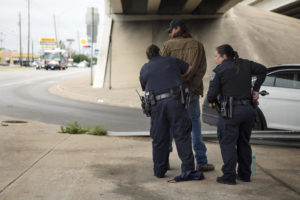Austin Police Officers arrest a man experiencing homelessness on Ben White and Manchaca. He was detained for jaywalking, but arrested for outstanding warrant for multiple tickets, including soliciting in a roadway and camping in public. CREDIT MIGUEL GUTIERREZ JR./ KUT NEWS